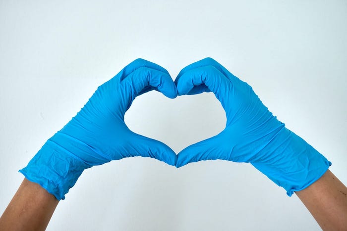 hands wearing gloves making heart shape